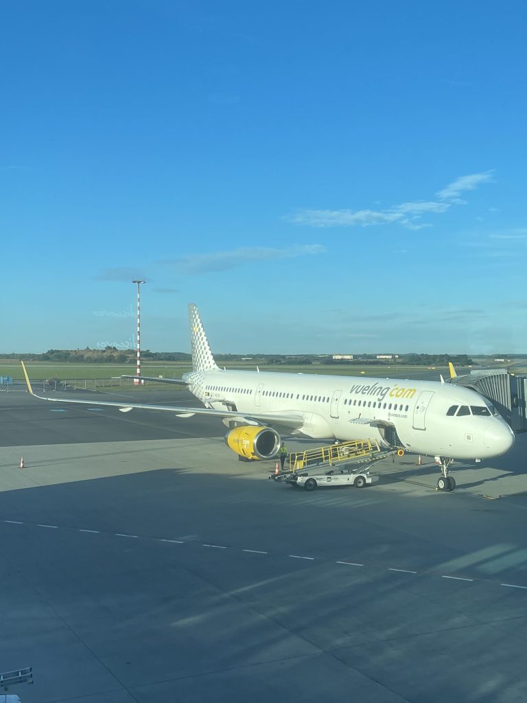 Vueling A321 parked at the gate on a clear morning.