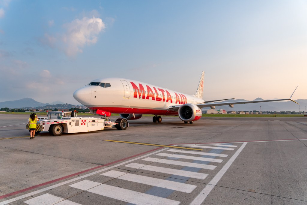Red and White Boeing 737-8-200 with Malta Air written on the fuselage pushing back from its stand.