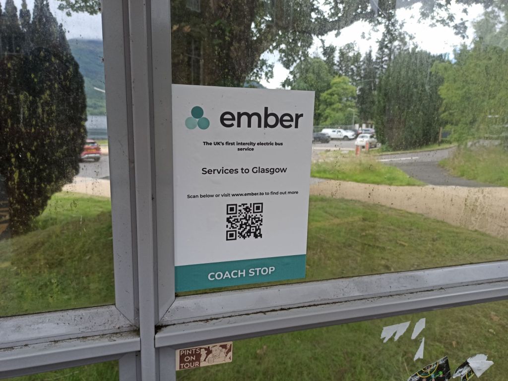 Picture of A4 Sign on bus shelter with Ember logo which reads "The UK's first intercity electric bus service, Services to Glasgow, Scan below or visit ember to find out more.